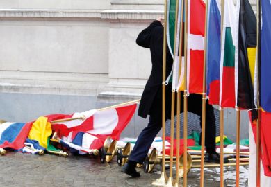 Suited man setting up row of international flags