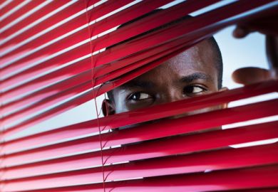 Suspicious man looking through venetian blinds