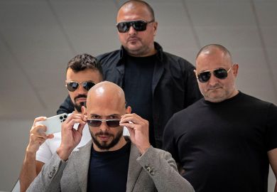  Andrew Tate walks with bodyguards to illustrate Should we be worried about Andrew Tate’s ‘anti-university’ university