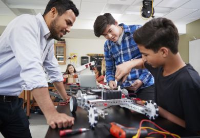 Teacher With Male Pupils Building Robotic Vehicle In Science Lesson