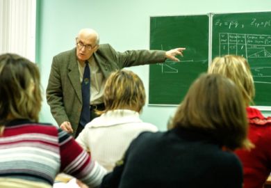 An elderly professor teaches from the blackboard