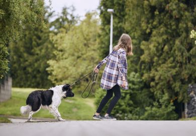 Teenage girl pulling stubborn dog