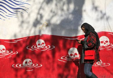 A woman walks past an anti-American murals following a possible US intervention against Iran on 28 January, 2026 in Tehran, Iran.