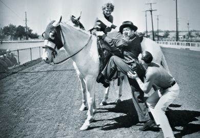 Young couple trying to help a man get onto his horse