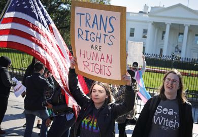 Woman holding up sign saying ‘trans rights are human rights’ at rally