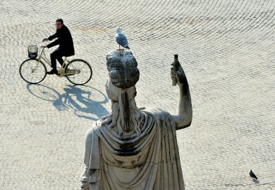 A man cycling past a statue in Rome