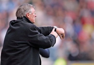 Alex Ferguson, manager of Manchester United, points to his watch