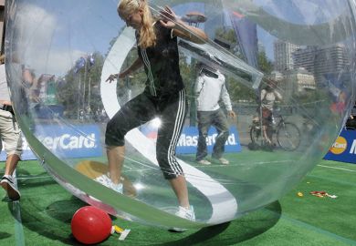 woman trying to kick ball from within a zorb ball / bubble