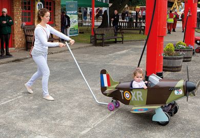 Woman pushing child in toy Spitfire plane