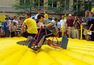 Visitors to the World Science Festival Street Fair peddle a square wheeled tricycle