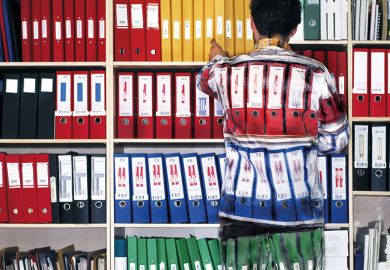 Man wearing camouflage suit matching shelves of folders
