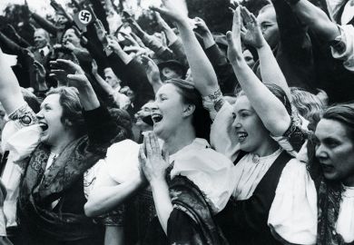 Ethnic Germans wearing traditional regional costumes give the Nazi salute and cheer Adolf Hitler on his visit to the town of Carlsbad in the Sudetenland
