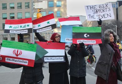 Muslim women hold signs with the flags of the banned countries during a massive protest against President Trump's travel ban outside of the U.S. Consulate in downtown Toronto