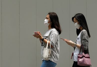 people wearing face masks and using mobile phones in Singapore people wearing face masks and using mobile phones in Singapore