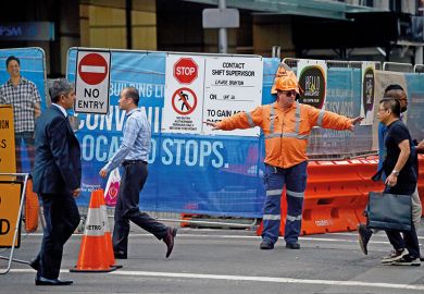 A worker directs pedestrians on a street in the central business district of Sydney