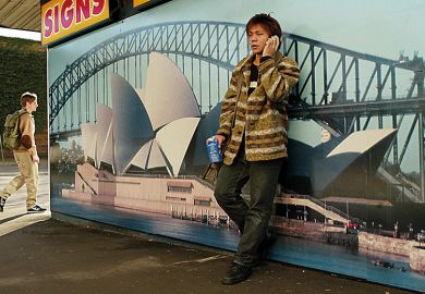 Asian student leaning against picture of Sydney Opera House, Australia