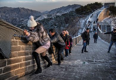 A Chinese tourist uses the scarf of a friend as she is helped while she and others  struggle to climb in the wind on an icy section of the Great Wall at Badaling, on a cold day after a snowfall