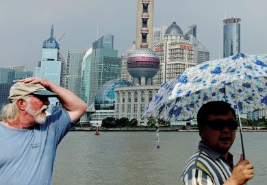 People walk along the Bund in front of the skyline of the city's financial district of Pudong, in Shanghai