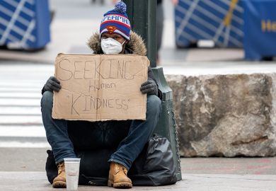 A homeless person wearing gloves and a protective mask sits with a sign that reads, "Seeking Human Kindness" amid the coronavirus pandemic on April 19, 2020 in New York City, United States. 