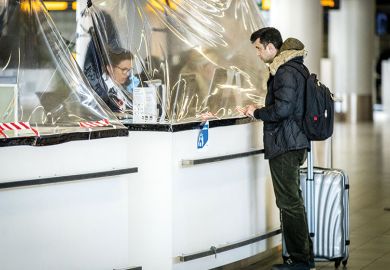 A passenger stands at an airline counter protected with a plastic tarpaulin on March 27, 2020, Netherlands