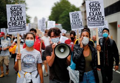 Students hold a placards as they march in central London on August 14, 2020 to protest against the downgrading of A-level results