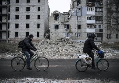 Two people cycle past bombed buildings in Ukraine Two people cycle past bombed buildings in Ukraine