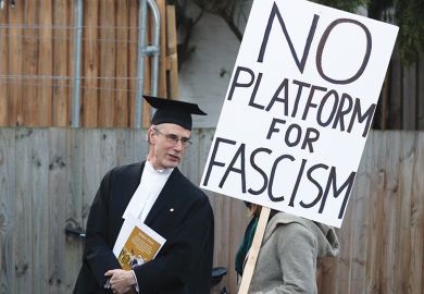 A proctor speaks to a protester holding a "No platform for fascism" placard