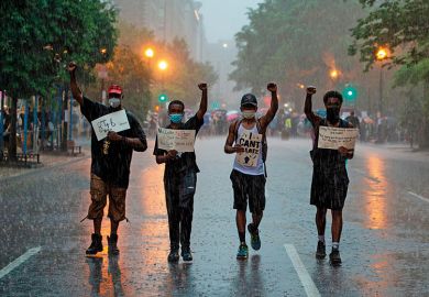 People holds signs as they walk in the rain after attending a Black Lives Matter protest in front of Lafayette Park next to the White House, Washington, DC on June 5, 2020