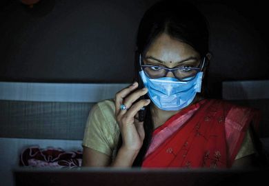 Young Indian Woman wearing mask working on her laptop and talking on phone Young Indian Woman wearing mask working on her laptop and talking on phone