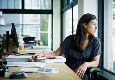 Woman looking out of window whilst at desk Woman looking out of window whilst at desk