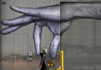 A woman in a mask walks past a mural of a hand on the side of a building in Midtown New York City  April 22, 2020 A woman in a mask walks past a mural of a hand on the side of a building in Midtown New York City  April 22, 2020
