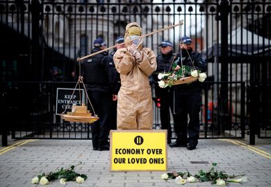 A protester from the group "Pause The System" stands beside the entrance to Downing Street in central London on March 17, 2020. A protester from the group "Pause The System" stands beside the entrance to Downing Street in central London on March 17, 2020.