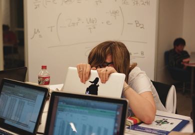 A student hides behind her laptop A student hides behind her laptop