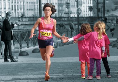 A female runner giving children a high five as she runs past.