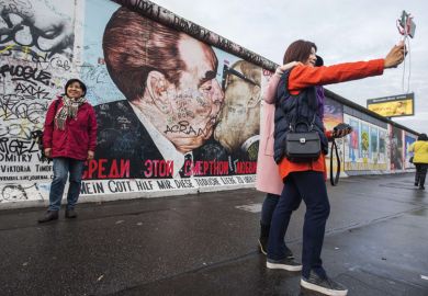 Tourists pose in front of Dmitri Vrubel mural, Berlin Wall