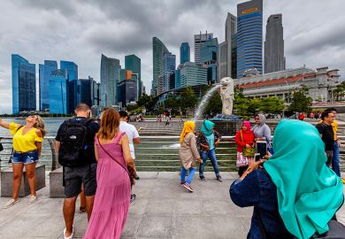 Tourists of various nationalities pose for photos in front of the Merlion statue and Singapore skyline, illustrating Singapore’s international nature Tourists of various nationalities pose for photos in front of the Merlion statue and Singapore skyline, illustrating Singapore’s international nature