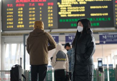 A traveller in a face mask at a railway station in Suzhou, China, illustrating the downturn in Chinese international students post-Covid
