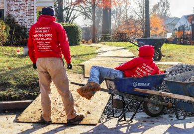 Tulsa USA Nov 15 2017 Construction workers waiting around at residential work site - one is lying in a wheel barrrow or construction cart in winter