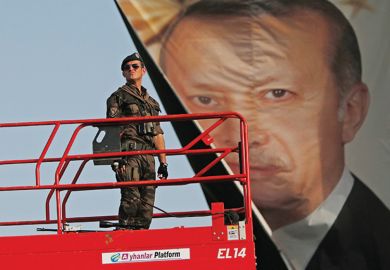 Turkish police officer standing in front of poster of President Recep Tayyip Erdoğan Turkish police officer standing in front of poster of President Recep Tayyip Erdoğan