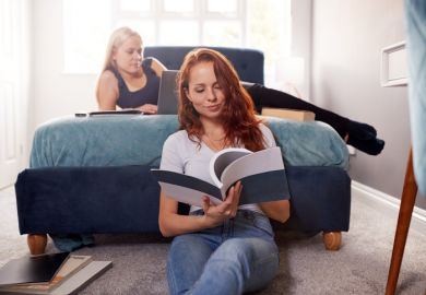Two Female College Students In Shared House Bedroom Studying Together