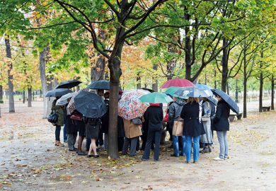 Group of people sheltering under umbrellas