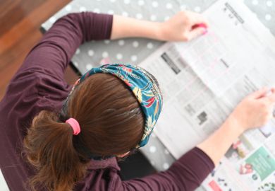 Unemployed woman searching for job in local newspaper