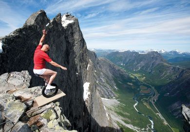 Man riding unicycle at edge of mountain