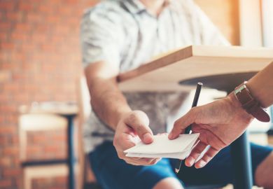 University students passing note in test, cheating the exam