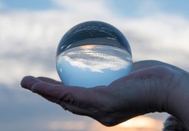 Hand holding a glass globe with a reflection of a sunset