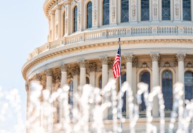 US Congress dome with foreground of water fountain splashing and American flag waving in Washington DC on capitol hill