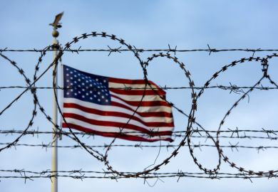 US flag behind barbed wire symbolising restrictions on international students coming to the US
