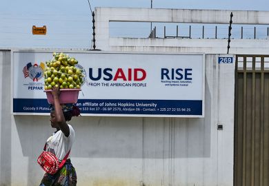 A street vendor walks past the USAID office in Abidjan, Ivory Coast