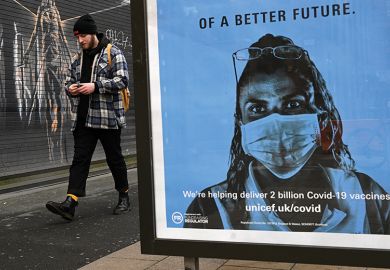 A pedestrian walks past a Unicef poster promoting Covid-19 vaccines, in Manchester, January 5, 2021, illustrating vaccine passports for campuses