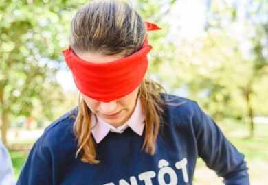 Valencia, Spain - April 7, 2019 Group of young people in an outdoor school playing cover their eyes with a red veil to find the partner, and thus develop social skills.